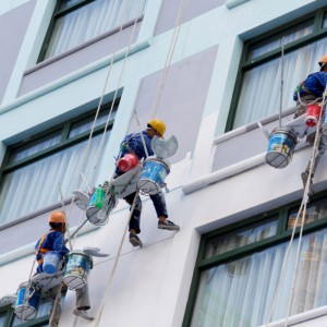 I lavoratori stanno dipingendo il colore nei grattacieli.
