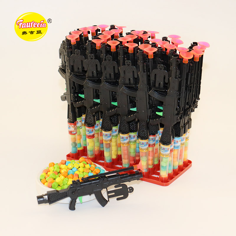 Гуманоид Фауресия нацеливается на зеленый пистолет-пулемет с курком и разноцветными конфетами